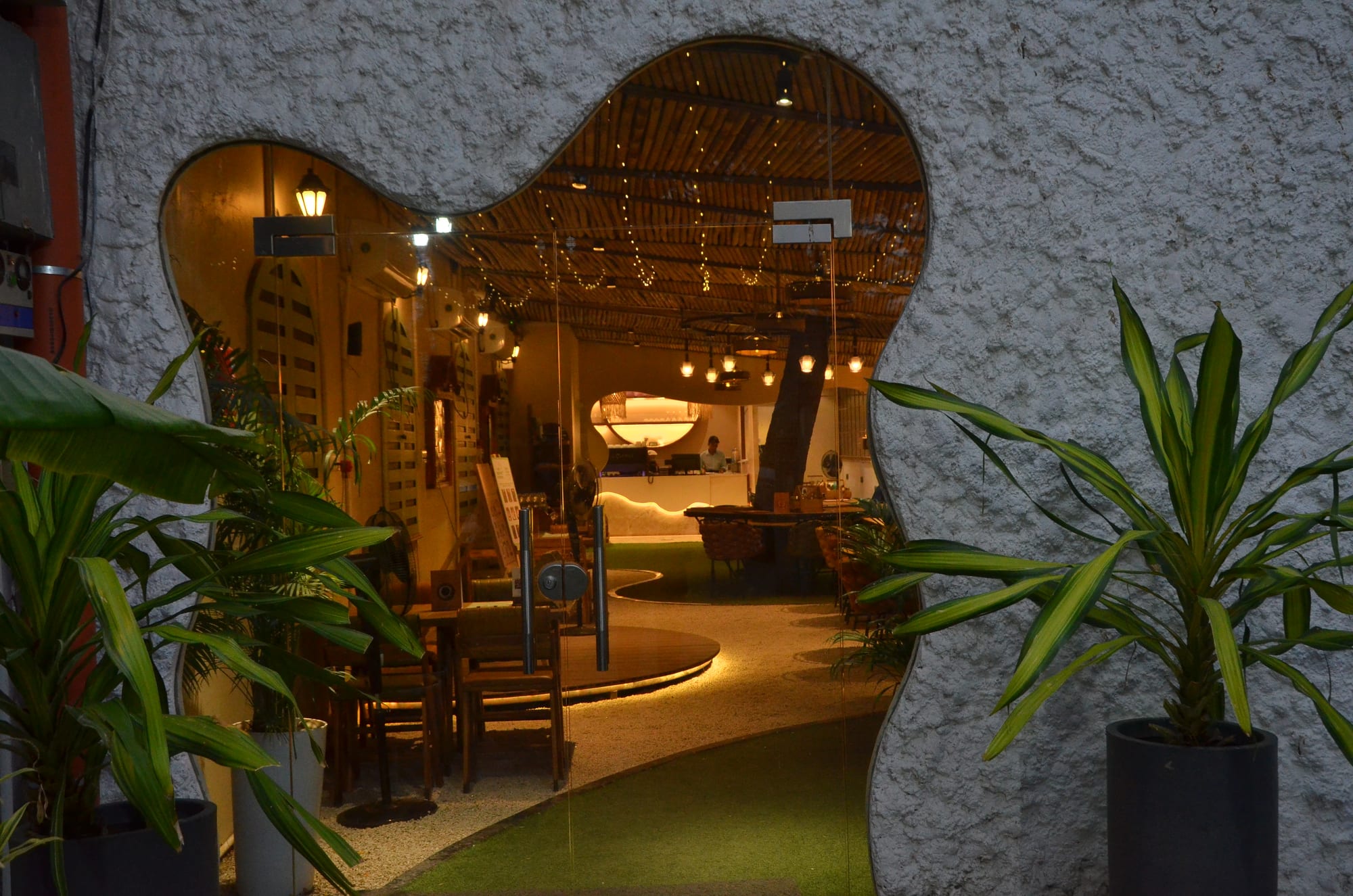 Seven O' Eleven entrance — an organic archway opening into the warm, bamboo-lit interior